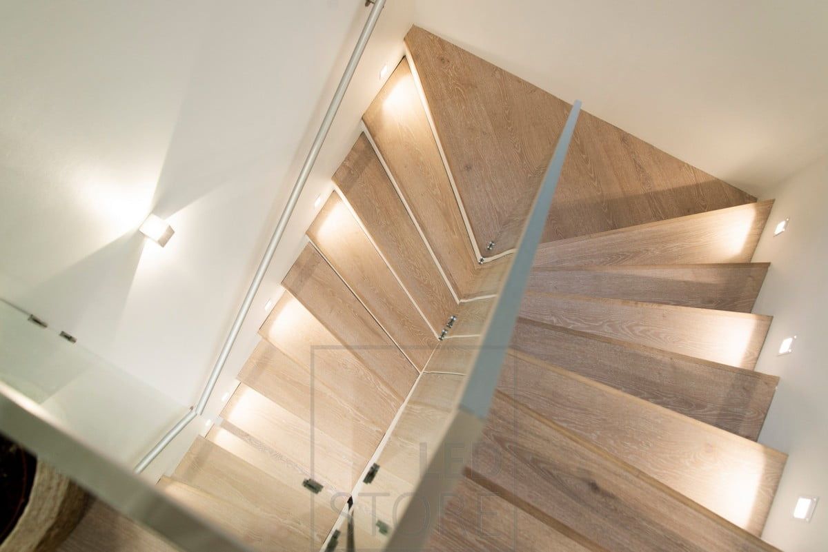 Staircase lighting, with a step lamp at each second step and bi-directional luminaires on the wall.